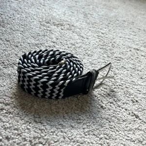 vit och svart flätat bälte - Säljer detta flätade bältet i ok skick. Det är 112cm långt, tveka inte med att fråga om ni undrar något