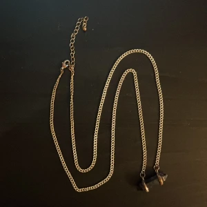 Halsband med blå kristallhänge - Snyggt halsband med en kedja i silverfärg och ett blått kristallhänge. Kedjan har en justerbar längd med karbinhake. Det silvriga hsr slitits bort lite med användning men syns bara på nära håll