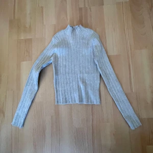 Beige ribbad tröja från Zara - Säljer en stilren beige ribbad tröja från Zara. Tröjan har en hög krage och långa ärmar, perfekt för kyligare dagar. Passar bra till både jeans och kjol. Perfekt för dig som gillar en enkel och snygg stil.