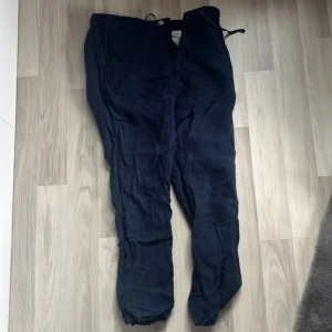 Mörkblå byxor från S.C.W. - Snygga mörkblå byxor från S.C.W. med en avslappnad passform. Byxorna har en enkel design med knappar och dragkedja framtill. Perfekta för en stilren look.