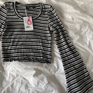 Svartvit randig croppad topp från Monki - Säljer en snygg svartvit randig topp från Monki. Den är croppad med långa ärmar och är ribbad💕ALDRIG ANVÄND!