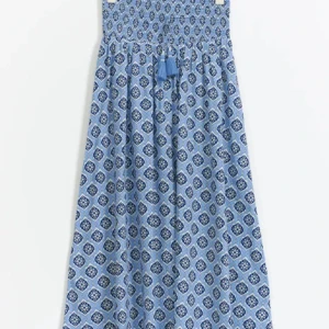 Långkjol - Snygg blå långkjol med ett unikt mönster i mörkblå och vita nyanser. Klänningen har en smockad överdel och dekorativa tofsar framtill. Perfekt för sommarens alla tillfällen! Använd typ Max 10 gånger förra sommaren och är i nytt skick💓köpt för 300💓