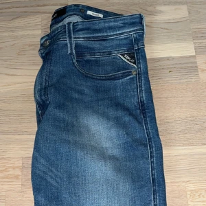 Blå jeans från Replay - Snygga blå jeans från Replay med en klassisk femficksdesign och diskreta slitningar. De har en knappgylf och är perfekta för en avslappnad stil. Strl 31/32 men skulle säga att den sitter om en vanlig 30/32. Modellen är slim fit ambass nypris 1799 mitt pris 500. Endast använda 2 gånger och är helt som nya.