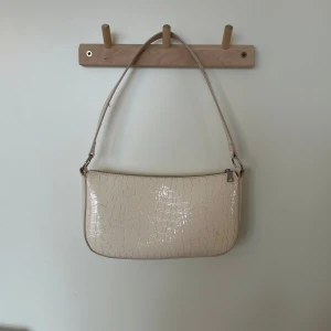 Snygg väska - Snygg beige axelväska med krokodilmönster och dragkedja. Perfekt för att ge din outfit en stilren touch. Väskan har en enkel design med en justerbar axelrem. Är dock lite smutsig men det går att ta bort 🩷🩷