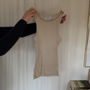Beige ribbad linnetopp från Weekday - Snygg beige ribbad linnetopp från Weekday. Perfekt för lager-på-lager eller att bära som den är. Den ärmlösa designen gör den idealisk för varmare dagar.