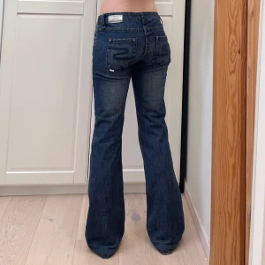 Lågmidjade bootcut jeans från gamla Bikbok🤩 - Midja 42x2 cm plus stretch, gren 18 cm o innerben 82 cm💕jae 169 o xs-s o håller in i midjan på bilderna. Obs kortade vilket syns på sista bilden men syns inte från utsidan!