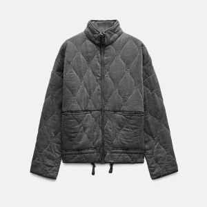 Grå quiltad jacka - Säljer en stilren grå quiltad jacka med dragkedja och hög krage. Jackan har en quiltad design och långa ärmar. Helt ny 