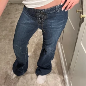 Jeans med snörning - Supersnygga mörkblåa jeans med snörning i midjan. Jag är 160cm och de är långa på mig. Midjemått: 40cm Innerbenslängd: 82cm
