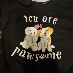 Svart sovtröja med hundmotiv från FB Sister - Säljer en svart sovtröja från FB Sister med ett gulligt tryck av två hundar och texten 'You are pawsome'. Perfekt för hundälskare! 🐾