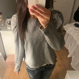 Grå tröja med puffärmar - Säljer en stilren grå tröja med puffärmar. Är perfekt för både vardag och speciella tillfällen. Den är i mycket bra skick, knappt använd!! Är i storlek S men sitter som S/XS💕