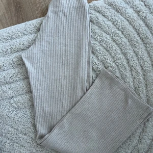 Beige ribbade byxor - Snygga beige ribbade byxor med en loose passform. Tajta vid låren. Perfekta för en avslappnad stil, dessa byxor är både bekväma och trendiga. De har en bred benstil som ger en skön känsla.
