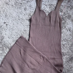 Beige ribbad klänning från Gina Tricot - Snygg beige ribbad klänning från Gina Tricot med breda axelband och en figurnära passform. Perfekt för en stilren look. Klänningen har en elegant design med subtila detaljer.