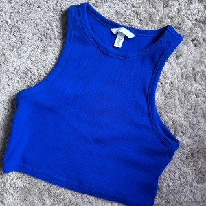 Blå ribbad linnetopp från H&M - Snygg blå ribbad linnetopp från H&M. Perfekt för varma dagar med sin ärmlösa design och croppade längd. Enkel och stilren, passar till många olika outfits.