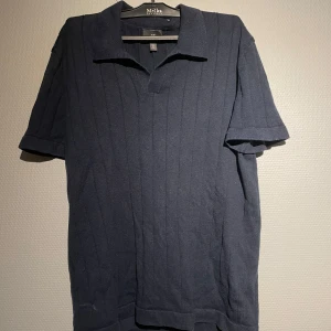 Mörkblå pikétröja från H&M - Säljer en stilren mörkblå pikétröja från H&M. Tröjan har korta ärmar och en klassisk krage. Perfekt för en avslappnad men ändå snygg look. Passar bra till både jeans och chinos.