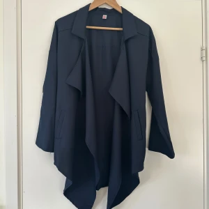 Mörkblå kofta, helt NY - Snygg mörkblå kofta / cardigan med lång ärm och en stilren design. Den har en öppen front och dekorativa fickor på sidorna. Perfekt för en elegant look.