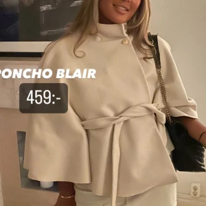 Beige poncho - Ponchojacka i beige med snygg knäppning vid halsen och bälte i midjan. Jackan har vida ärmar och en stilren, minimalistisk look. Perfekt för dig som vill ha en trendig och chic vibe till hösten eller våren.
