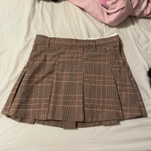 Brun rutig plisserad kjol från H&M - Superfin brunrutig kortkjol från H&M med klassiskt plisserad design och bälteshällor i midjan😋