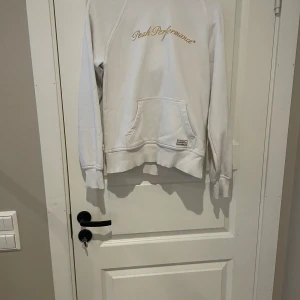Vit hoodie från Peak Performance M - Säljer en vit hoodie från Peak Performance i storlek M. Tröjan har guldigt broderat logotyp på bröstet, känguruficka framtill och huva med broderad detalj. Tillverkad i mjuk bomullsmix, perfekt för chill dagar eller när du vill ha en clean look. (Om du vill köpa köp på Vinted brage2011)