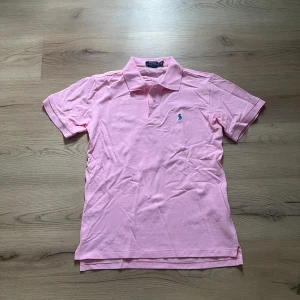 Rosa pikétröja från Polo Ralph Lauren - Säljer en rosa pikétröja från Polo Ralph Lauren. Tröjan har klassisk krage, korta ärmar och blå broderad logga på bröstet. Tillverkad i mjuk bomull, perfekt för en fräsch och stilren look. Ny skick, är S men passar mer som M.