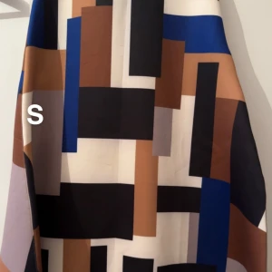 Färgstark mönstrad kjol - Snygg kjol med grafiskt rutigt mönster i svart, blått, brunt, beige och vitt. Kjolen har en modern look med raka linjer och blockfärger, perfekt för dig som gillar att sticka ut. Tillverkad i ett mjukt och följsamt material.🌸Sparsamt använd. Storlek s