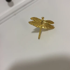 Guldfärgad ring med trollslända -  RIKTIG IOAKU RING.  💗                                            Cool statementring i form av en trollslända i guldfärgad metall. Ringen har fina detaljerade vingar och en unik design som verkligen sticker ut. Perfekt för dig som vill ha något annorlunda och trendigt på fingret.