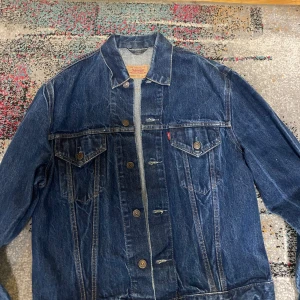 Levi's blå jeansjacka XL - Klassisk blå jeansjacka från Levi's i modell 70500. Jackan har två bröstfickor med knappar, snygga sömmdetaljer och den ikoniska röda Levi's-taggen. Perfekt oversized fit. Stängs med knappar framtill. Den är perfekt på lämgden men kanske lite mer oversized för mig som har storlek s 