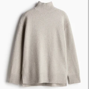 Beige polotröja  - Mysig beige polotröja med hög ribbad krage och avslappnad passform. Tröjan har långa ärmar och breda ribbade muddar vid ärmslut och nederkant. 