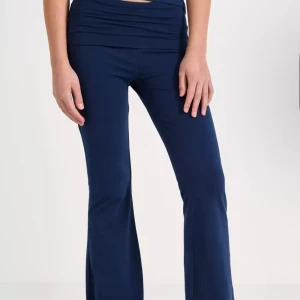 Mörkblå bootcut yogabyxor - Mörkblå bootcut yogabyxor med bred, vikt linning och stretchigt material. Snygg passform med utsvängda ben och mjuk känsla, perfekta för en avslappnad look eller träning. Färgen är djupblå och tyget är följsamt och bekvämt.