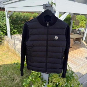 Moncler cardigan - Säljer en svart Moncler cardigan med stickade svarta ärmar. Tröjan är i storlek M och passar mellan 170-175 cm. Använd ett antal gånger men inga defekter över huvud taget. Ställ frågor om det behövs, priset går att diskuteras.