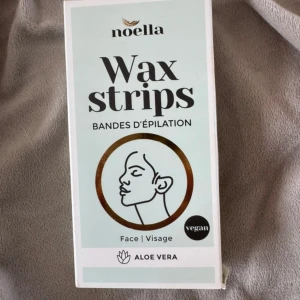 Noella Wax Strips för ansikte - Noella Wax Strips för ansiktet med aloe vera. Kommer i en stilren ljusgrön förpackning. Observera att förpackningen är lite trasig. Innehåller 9 vaxremsor och 2 våtservetter för ansiktet. Stenciler för ögonbrynen saknas.