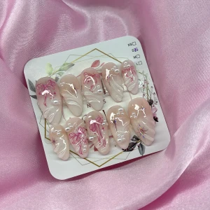 LilyDream (S);Medium Almond - Snygga gelé press-on naglar i en medium mandelform med nude bas, dekorerade med vita 3D-pärlor, vit fade och rosa rosetter, 3D handmålad nailart. Naglarna har en glansig finish och kommer i storlek S: 15 mm, 11,5 mm, 12 mm, 11 mm, 9 mm. Perfekt för dig som vill ha en söt och trendig look.