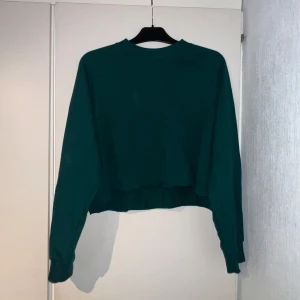 Grön croppad tröja från Monki - Säljer en grön croppad tröja från Monki i storlek M. Tröjan har långa ärmar, ribbade muddar och en relaxed passform. Perfekt för dig som gillar en enkel men snygg stil. Materialet känns mjukt och skönt mot huden. Passar allt från xs-xl. Använd fåtal gånger❤️