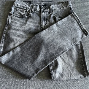 Gråa raka jeans från Levi’s - Säljer ett par gråa  jeans med rak passform och klassisk femficksdesign. Jeansen har en snygg tvättad finish som ger en cool vintagekänsla. Tillverkade i mjukt jeanstyg och passar perfekt till en avslappnad stil. Hör av er vid intresse/ frågor!