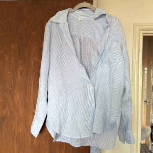 Blåvit randig skjorta i linne - Snygg blåvit randig skjorta i luftig linneblandning. Klassisk krage, långärmad med knappar vid ärmslut och framtill. 