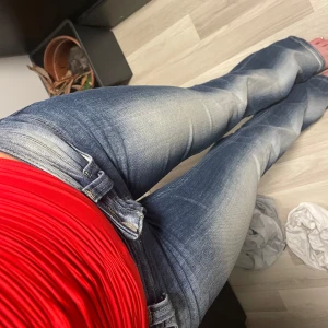 Blå bootcut jeans från Cheap Monday - Snygga blå jeans från Cheap Monday med bootcut-modell och slitna detaljer framtill. Jeansen har klassisk femficksdesign, låg midja och en cool vit logopatch bak. Perfekta för dig som gillar en retro vibe och vill ha ett par jeans som sticker ut.