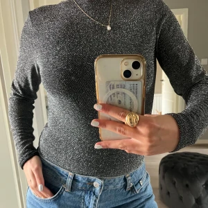 Glittrig Body - Perfekta festbodyn😍! Nästan aldrig använd och har en sån fin öppning i ryggen, perfekt till ett par stora jeans eller en kort kjol med boots! Stl. M men passar S-M, jag har vanligtvis XS-S i toppar/bodys.