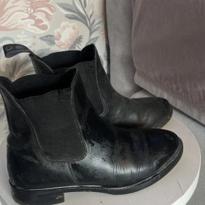 Svarta chelsea boots från CRW - Säljer ett par klassiska svarta chelsea boots från CRW i storlek 37. Skorna har elastiska paneler på sidorna och dragflikar bak för enkel påtagning. Perfekta till många olika outfits och tillfällen. Används främst som ridskor!