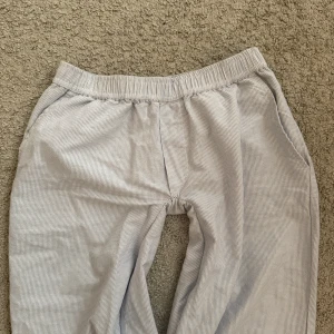 Randiga byxor från Madlady. Ultra low waist - Ljusblå och vita randiga byxor från Madlady med elastisk midja och avslappnad passform. Byxorna har fickor på sidorna och är perfekta för en chill och bekväm stil samt en ficka där bak. Modellen är S/Tall. Jag har sytt om dom stjälv med det syns inte.