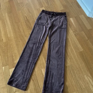 Bruna mjukisbyxor med snörning - Säljer ett par bruna mjukisbyxor med bred resår och snörning i midjan. Byxorna har stora framfickor och bakfickor med lock och knappar. Mjukt material som känns skönt mot huden, perfekt för en avslappnad stil.