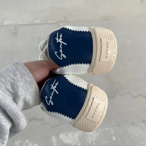 sneakers från Eytys - Säljer ett par snygga sneakers från Eytys i vitt och blått med signaturdetalj på hälen. Dom är helt oanvända. Säljer billigt har för mycket skor 