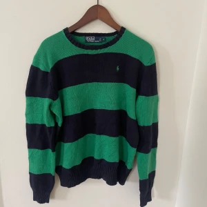 Randig tröja från Polo Ralph Lauren - Säljer en grön och marinblå randig tröja från Polo Ralph Lauren. Tröjan är i 100% bomull, har långa ärmar och klassisk passform. Perfekt för dig som har en tilren look. Inga tecken på användning!