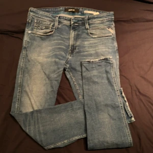 Blå Replay Anbass jeans - Säljer ett par blå jeans från Replay, modell Anbass. Jeansen har klassisk femficksdesign, slim passform och gjorda i slitstarkt material. Märkeslogga på bakfickan och läderpatch i midjan. Perfekta för dig som gillar stilrena jeans med modern passform. Jeansen är i W33 och L32 Skriv kring funderingar!