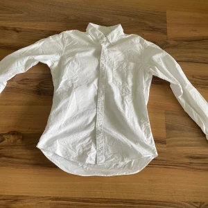 Vit skjorta från Uniqlo - Klassisk vit skjorta från Uniqlo i slim fit-modell. Skjortan har långa ärmar, knappar framtill och en bröstficka. Perfekt för en clean och stilren look.