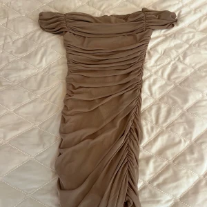 Beige offshoulder klänning med rynkade detaljer - Säljer en snygg beige offshoulder klänning med rynkade detaljer och dragkedja bak. Klänningen har en tight passform och är perfekt för dig som vill sticka ut. Supersnygg till sommarens alla tillfällen! Från SHEIN 