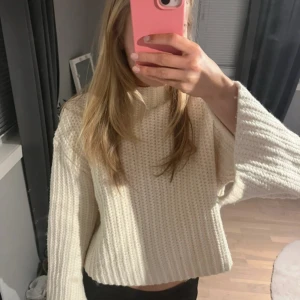 Vit stickad croppad tröja från Zara - Säljer en vit, grovstickad tröja från Zara med lite högre hals och vida ärmar med slits. 💕Enkel att styla till olika outfits. Supermysig!