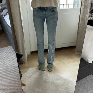 Ljusblå bootcut jeans från Divided - Säljer ett par ljusblå jeans från Divided med klassisk femficksdesign och bootcut-ben. Storlek 34. Sitter snyggt och är i fint skick. Jag är 169 cm lång, och på bilderna är mitt innerbensmått ca 82,5 cm och midjemått (platt mätt på mig) ca 31 cm.