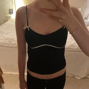 Söt topp - Svart topp med vita detaljer och rosetter. Storlek XS från Zara.