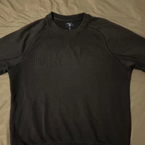 Svart sweatshirt från GANT - Säljer en svart sweatshirt från GANT med broderad logga framtill. Tröjan har rund halsringning och långa ärmar. Perfekt för en stilren och avslappnad look.