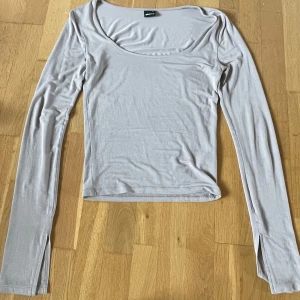 Ljusgrå/beige långärmad topp från Gina Tricot - Säljer en ljusgrå/beige långärmad topp från Gina Tricot. Toppen har en rundad, något djupare halsringning och är tillverkad i ett mjukt, stretchigt material. Ärmarna är raka och slitsade längst ned. Perfekt för att styla med jeans eller kjol. 
