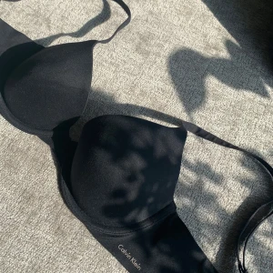 Svart bh från Calvin Klein  - Svart vadderad bh från Calvin Klein med justerbara axelband och diskret logga på sidan. Enkel och stilren design som passar perfekt under alla typer av toppar.